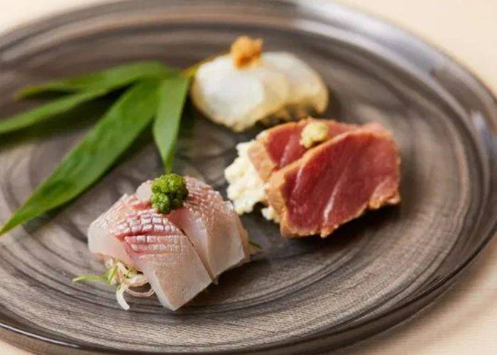 A serving of quality sashimi at Shibuya Sushiki, garnished with wasabi and leaves.